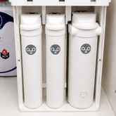Drie witte waterfilters met a2o-logo onder keukenkast, voor zuiver en kalkvrij water