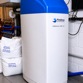 Waterontharder met blauwe kap en zouttabletten, voor zacht zuiver water in de technische ruimte